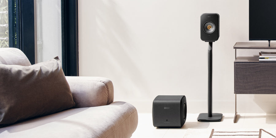 KEF Black KC62 Subwoofer naast een KEF LSX II op een S1 statief in een huiskamersetting