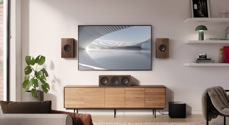 Stijlvolle homecinema-opstelling met KEF Q Series luidsprekers in walnootafwerking, een centerspeaker en subwoofer, rondom een muur-gemonteerde tv in een modern woonkamerinterieur met Scandinavische invloeden.