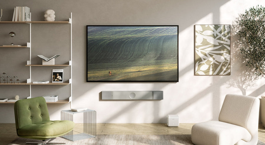 Moderne woonkamer met aan de muur gemonteerde tv en stijlvolle KEF-soundbar, als voorbeeld van een hoogwaardige thuisbioscoopopstelling in natuurlijk licht