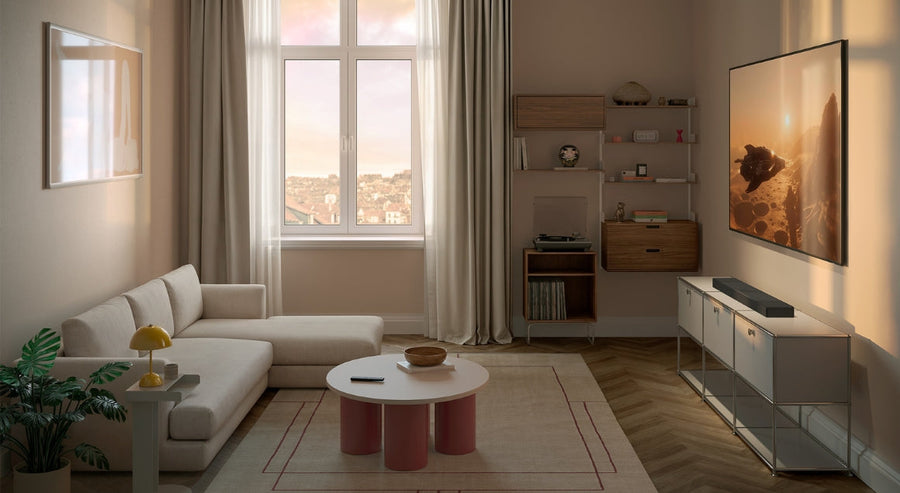 Moderne woonkamer met een aan de muur gemonteerde tv, beige hoekbank, zacht natuurlijk licht en minimalistische inrichting in neutrale tinten.